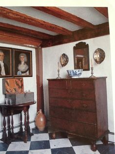 an antique dresser in the corner of a room with paintings on the wall and pictures above it