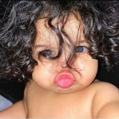 a close up of a baby with curly hair