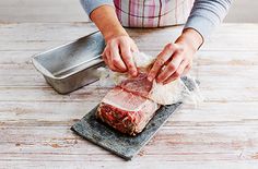 a person preparing food on top of a wooden table