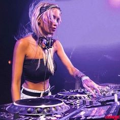 a woman with headphones is playing music on a dj's turntable at a concert