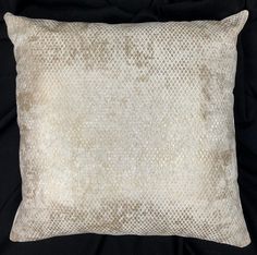 a white and beige snake skin pillow on a black background