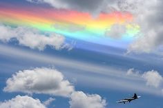 an airplane flying under a rainbow colored sky