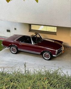 a maroon car parked in front of a garage