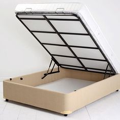 an open bed frame sitting on top of a white floor in front of a wall