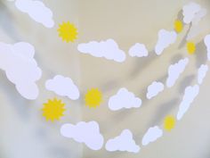 paper clouds, sun and stars are hanging from the ceiling in front of a wall