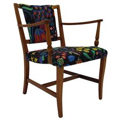 an upholstered wooden chair with colorful fabric on the armrests and back