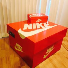 two nike boxes sitting on top of a hard wood floor next to a white wall