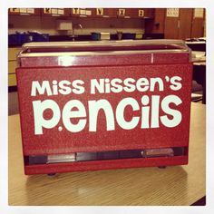 a red lunch box with the words miss nissen's pencils on it