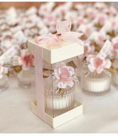 small glass vases with pink flowers in them on a white tablecloth covered table