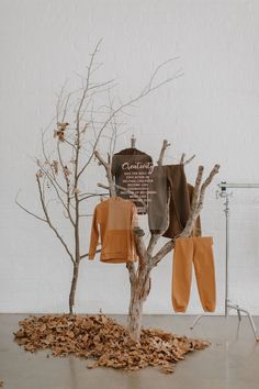 Clothes in hues of brown hanging from a tree with leaves on the bottom. Fall Theme Event, Clothing Creative Ads, Fashion Display Ideas, Clothes Display Ideas, Kids Shop Design, Clothing Display Ideas, Fall Store Displays, Boutique Clothing Store Design, Baby Store Display