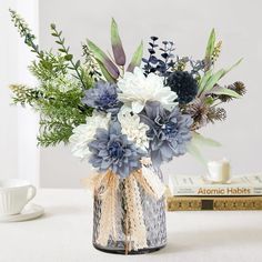 a vase filled with blue and white flowers on top of a table next to a book