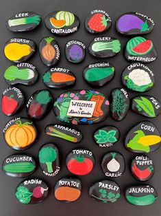 a bunch of magnets that are on top of a black surface with words and vegetables painted on them