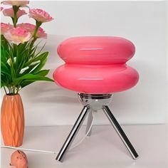 a pink object sitting next to a vase with flowers in it