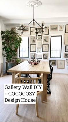 a wooden table sitting in the middle of a room with pictures on the wall behind it