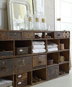 an old dresser with many drawers in front of a mirror and other items on it