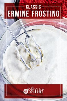 a glass bowl filled with white frosting on top of a counter next to a red towel