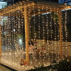 an outdoor gazebo covered in fairy lights with people sitting at the table under it