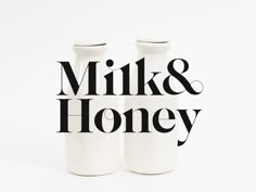 two white vases with the words milk and honey printed on them, sitting side by side