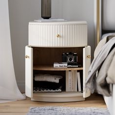 a small white cabinet with books and a camera on the shelf in front of it