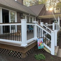 a dog is sitting on the front porch next to a fence and steps that lead up to a house