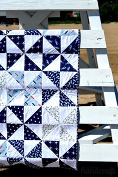 a blue and white quilt sitting on top of a wooden bench