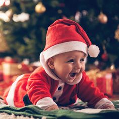 a baby wearing a santa hat on top of a blanket