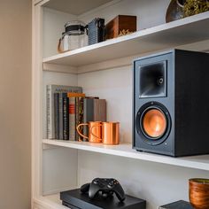 there is a speaker and some books on the shelf