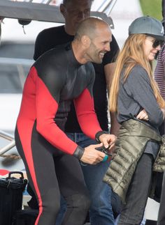 a man and woman in wetsuits standing next to each other on a boat