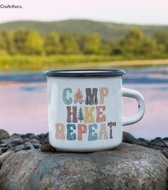 a camp mug is sitting on some rocks by the water