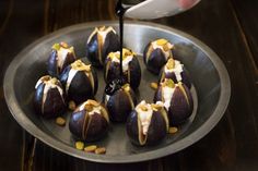 a plate full of chocolate covered figs with white frosting and pistachio