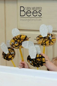 a person holding up some paper flowers in front of a door with the words bees on it