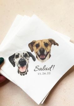 a person holding a napkin with two dogs on it and the words salud printed on it