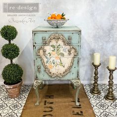 a blue cabinet sitting on top of a rug next to two candles and a potted plant