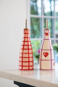 three vases with hearts on them sitting on a table in front of a window