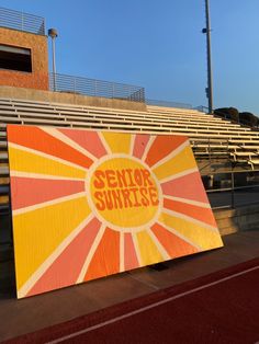 an orange and yellow sign that says senior sunrise on it in front of some bleachers