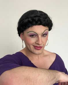 a woman with black hair and purple makeup is posing for the camera while wearing an evil mask