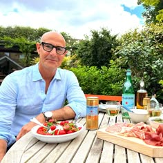 a man sitting at an outdoor table with food and drinks on the outside patio area