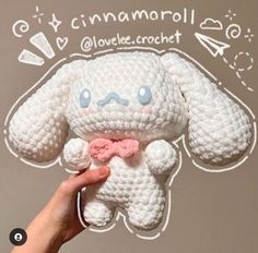 a hand holding a small white crocheted stuffed animal with a pink bow around its neck