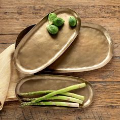 asparagus on two serving trays, one with green leaves and the other without