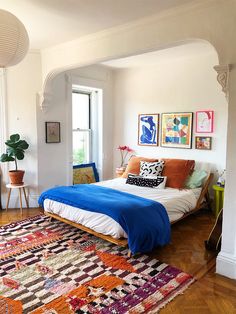 a bed sitting in the middle of a living room next to a window filled with lots of furniture