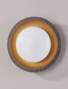 a yellow and white bowl sitting on top of a counter next to a gray wall