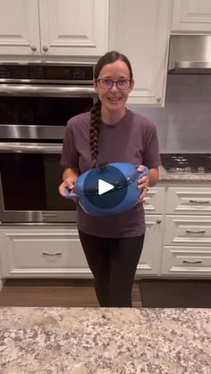 a woman standing in a kitchen holding a bowl