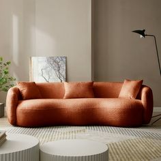 an orange couch sitting on top of a rug in a living room next to a lamp