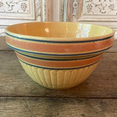 an orange and blue bowl sitting on top of a wooden table