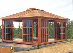 a wooden gazebo sitting on top of a dirt field