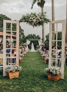 an outdoor ceremony with white chairs and flowers on the aisle, surrounded by palm trees