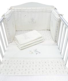 a white crib with sheets and blankets on it's sides, next to a blanket