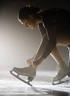 a woman riding on top of a pair of roller skates in the dark with lights behind her