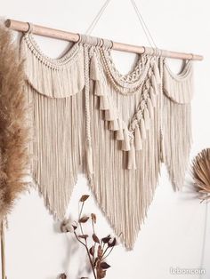 there is a wall hanging made out of macrame and some feathers on it