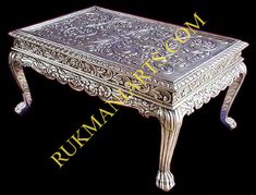 a silver table with an ornate design on the top and bottom, sitting against a black background